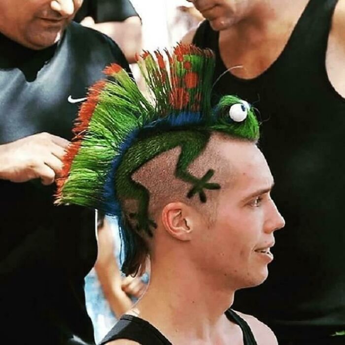 A man with a bold, vibrant green and orange hairstyle shaped like a frog, showcasing unique hair art.