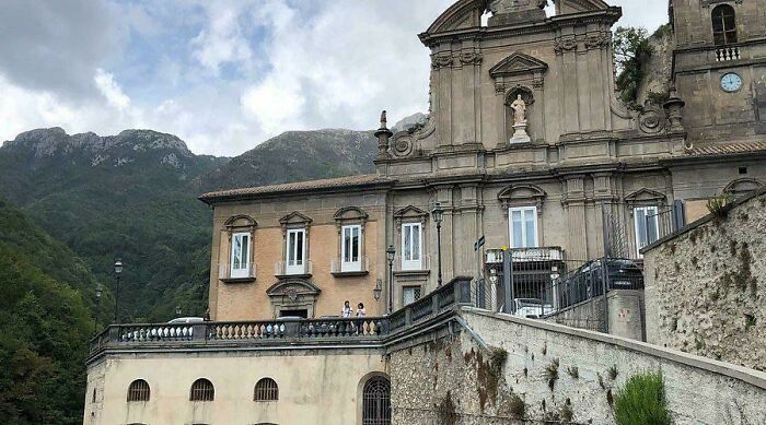 An ancient European building with a dome and statues, nestled in a mountainous landscape, a testament to the Middle Ages.