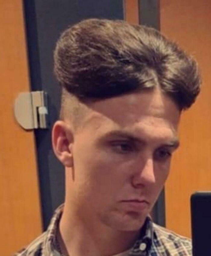 Young man with a high, rounded, and parted hairstyle, exemplifying a bold hairstyle choice.