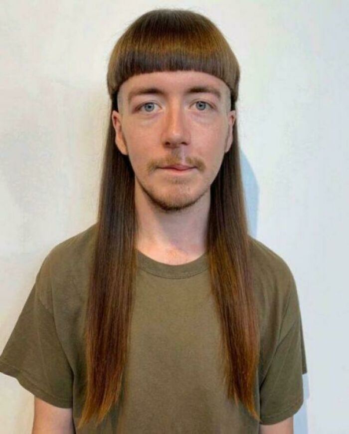A man with a bold, long bowl-cut hairstyle with very long sides, looking directly at the camera.