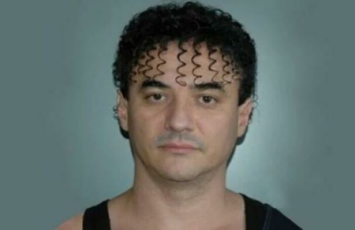 A man with an unusual bold hairstyle featuring tight, curly, spring-like bangs across his forehead.