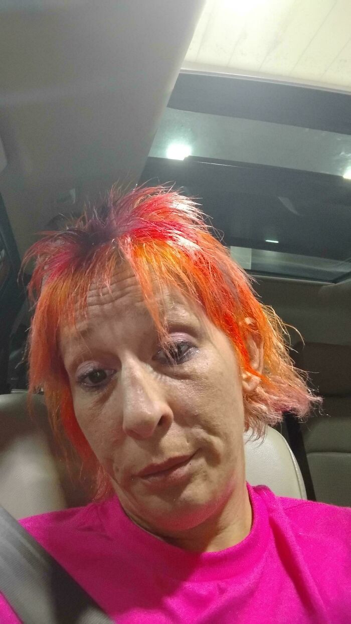 A woman in a car with bold orange, spiky hairstyles.