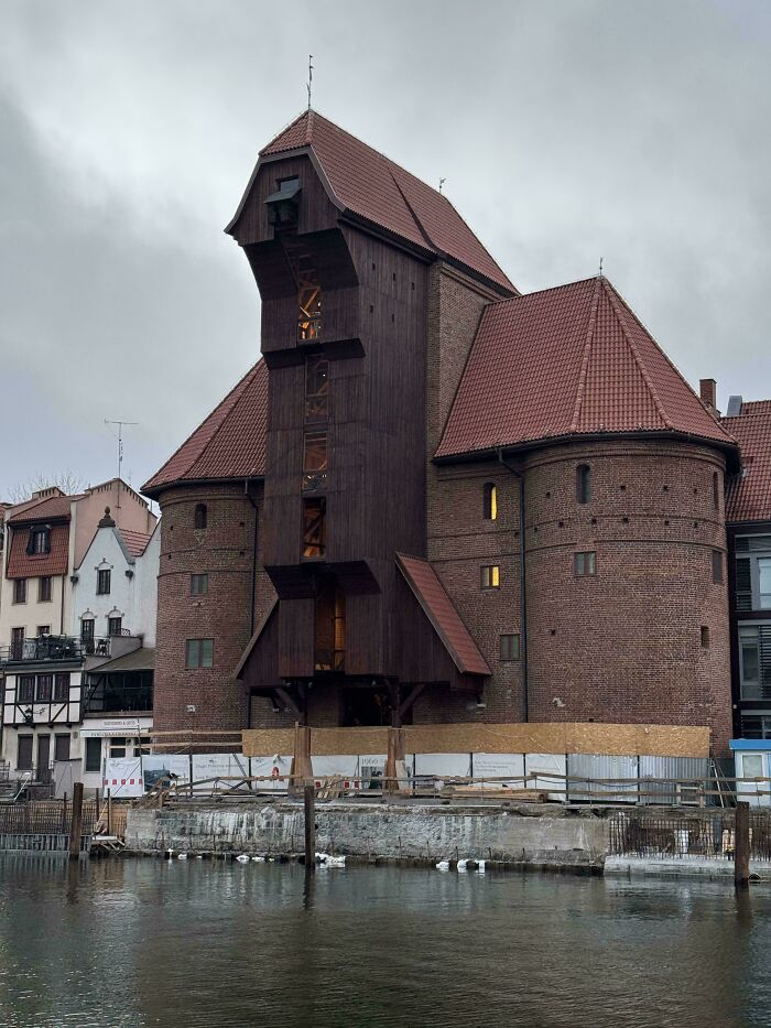 A large medieval port crane by a river, illustrating the fascinating architecture of the Middle Ages.