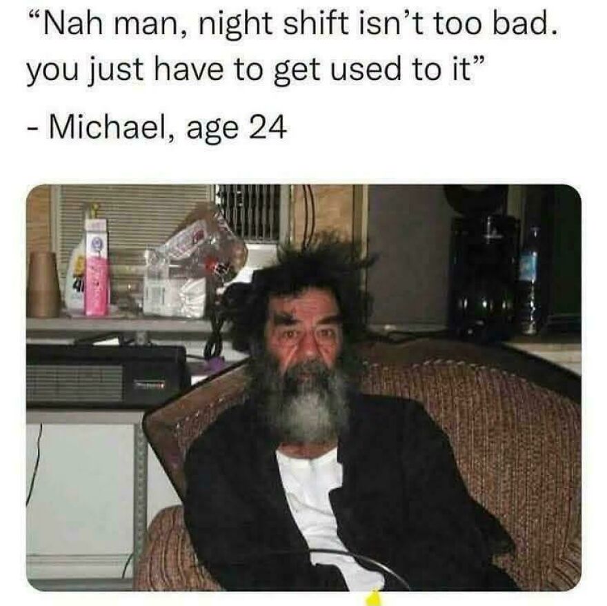 A disheveled man with a long beard and wild hair sits, depicting a humorous real-life meme about night shifts.