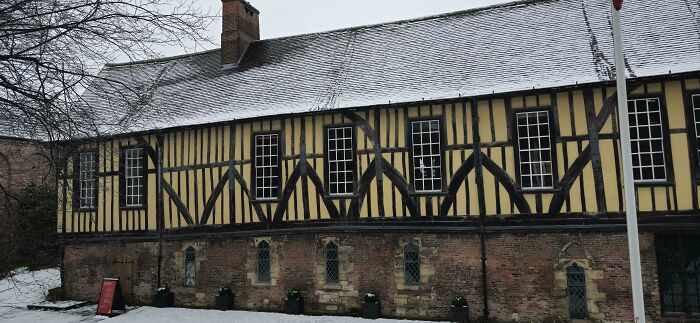 A half-timbered building with snow on the roof, representing human history of the Middle Ages.