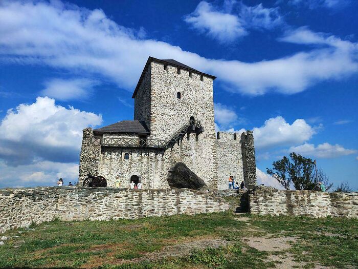 Medieval stone castle with a prominent tower against a bright blue sky, a testament to the Middle Ages.