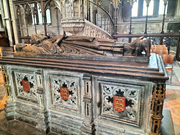 A grand stone sarcophagus with royal crests, depicting human history of the Middle Ages.