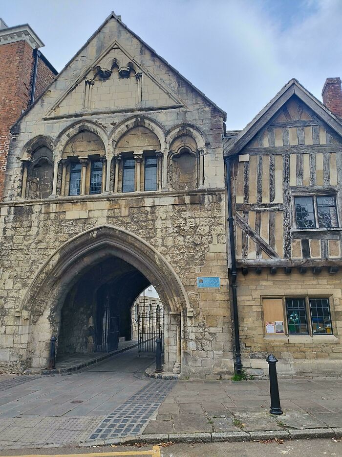 Historic stone archway building with timber-framed section, revealing the architectural style of the Middle Ages.