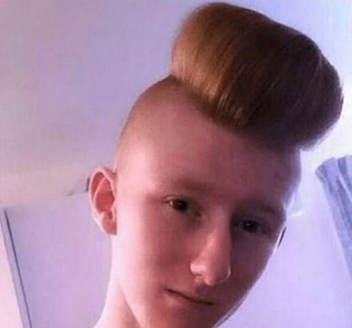 Young man with a high, pompadour-like hairstyle and shaved sides, displaying bold hairstyles.