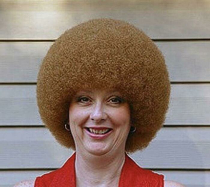 A woman smiling with an enormous, perfectly round afro hairstyle, showcasing a very bold look.
