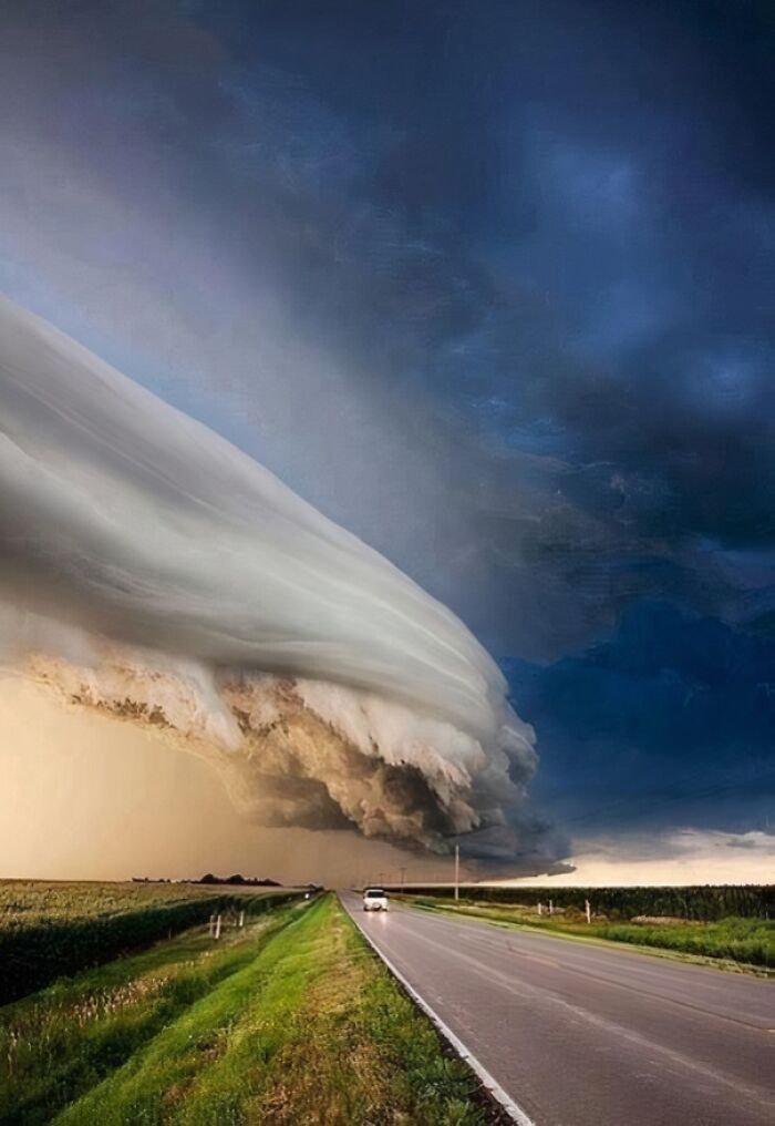 A powerful storm cloud stretches across the sky over a long, empty road, showcasing a fascinating and wildly different photo of the USA.