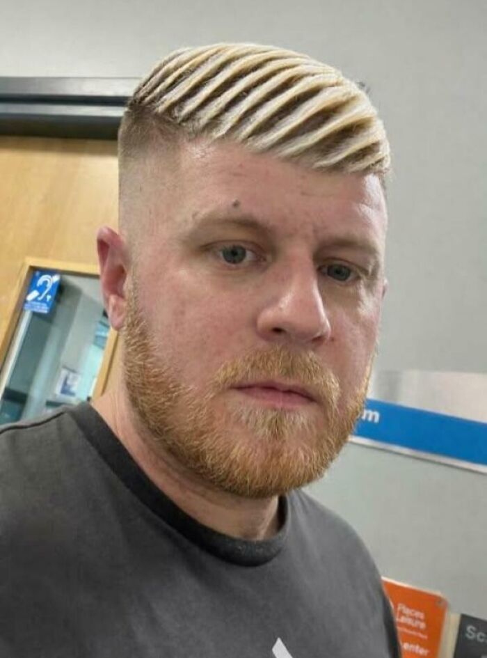 A man with a blonde, striped fade haircut and a beard, displaying a bold hairstyle.