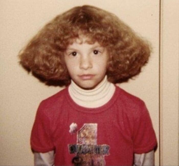 A young girl with a large, frizzy, light brown afro-like hairstyle, highlighting bold hairstyles.
