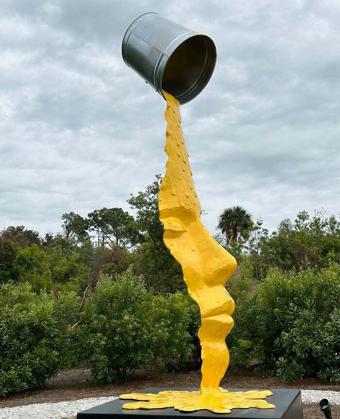 A large outdoor sculpture of yellow liquid pouring from a bucket, forming a human profile, a brilliant design choice.