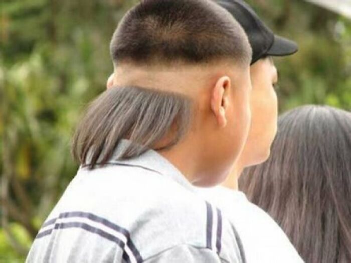 A young person with a short haircut on top and long hair cascading from the back, showcasing bold hairstyles.