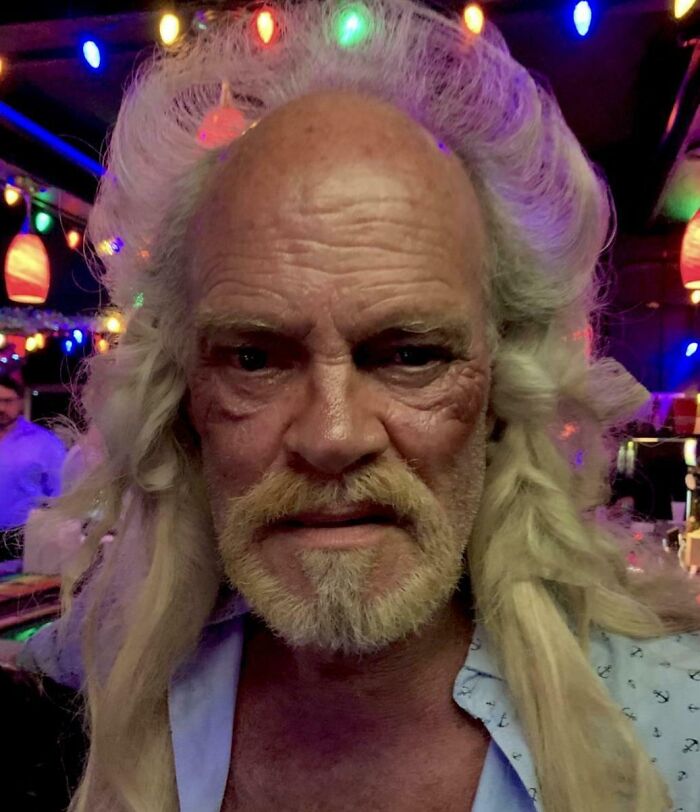 Older man with long blonde curly hair and beard, wearing festive lights, a truly bold hairstyle.