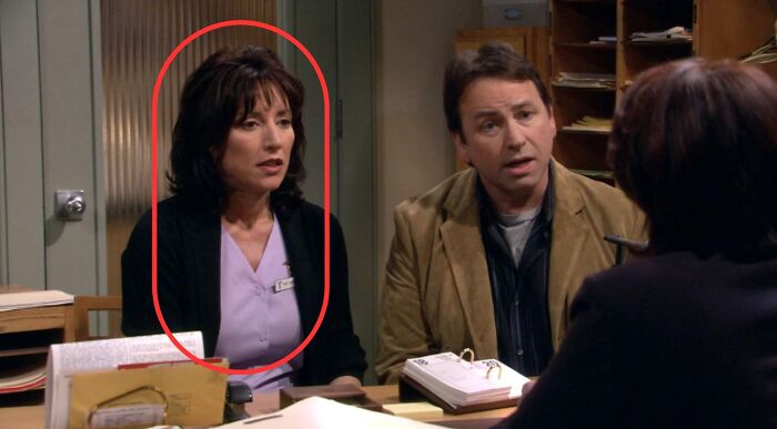 Cate Hennessy circled in red, wearing a light purple scrub top, revealing her profession. What career does Cate Hennessy pursue in 8 Simple Rules?