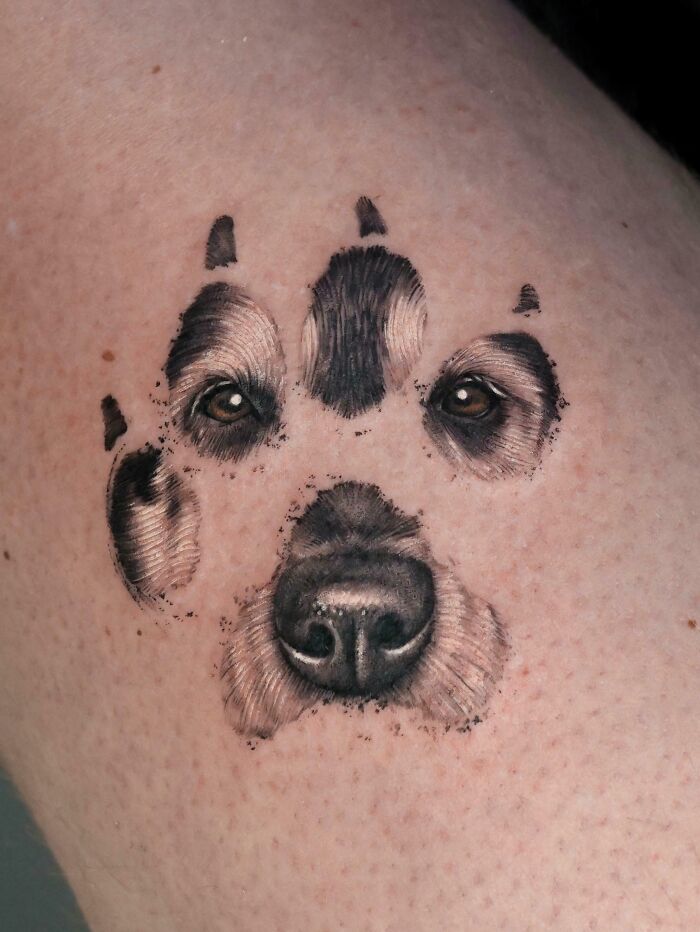 A stunning tattoo of a dog's paw print with detailed eyes and nose, looking realistic and impressive.