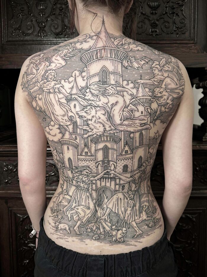 An elaborate and stunning full-back tattoo depicting a detailed medieval castle scene with mythical figures and creatures, illustrating stunning tattoos.