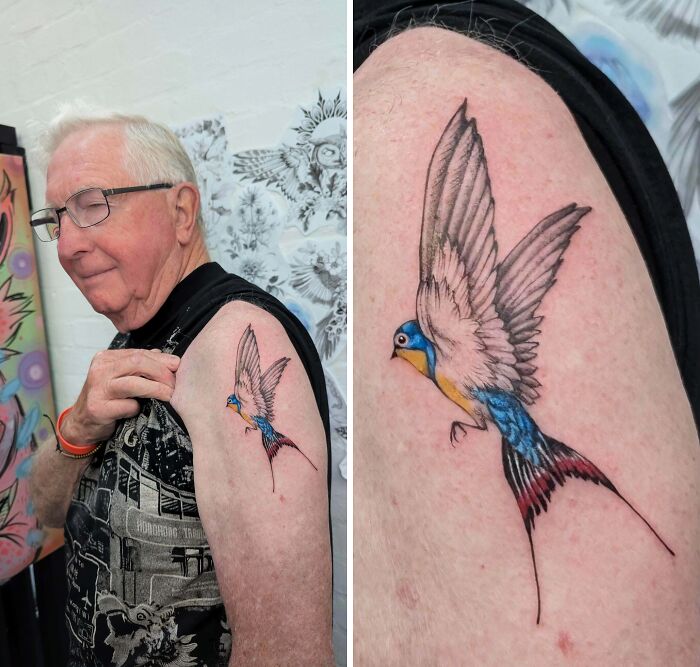 An elderly man proudly displaying a stunning tattoo of a colorful swallow with outstretched wings on his upper arm.