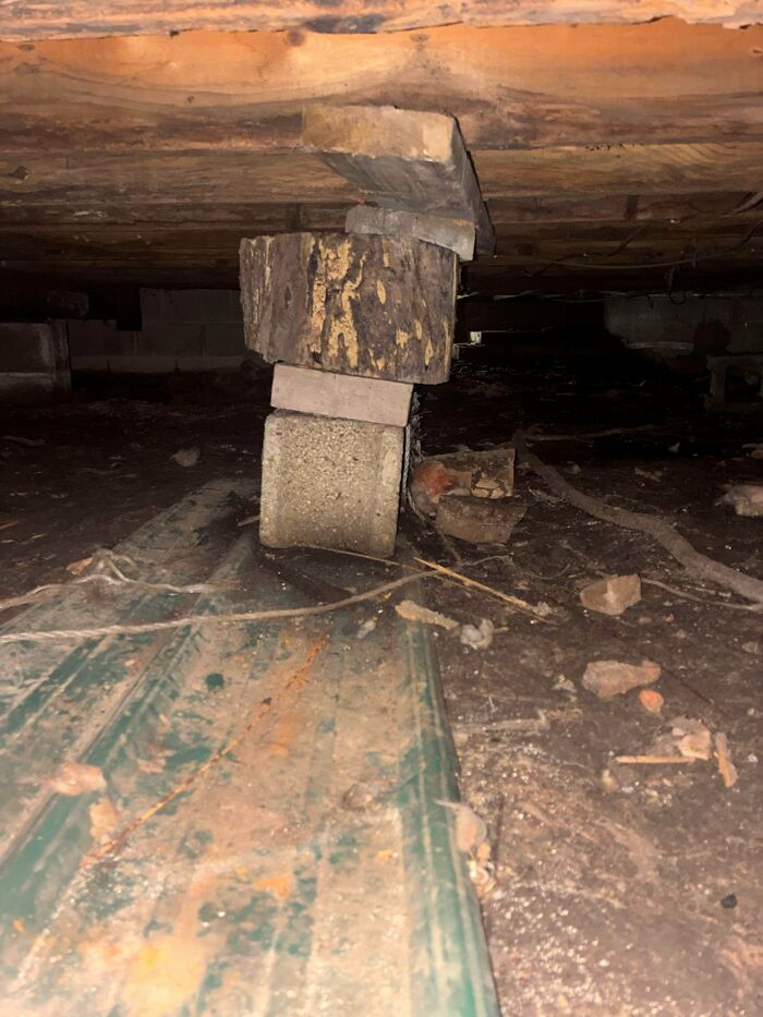 Stacked wood and concrete blocks providing support under a floor, an example of clever solutions from random junk.
