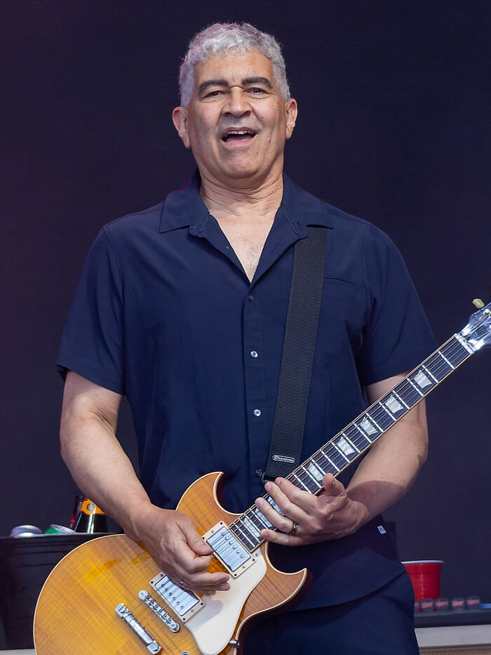 Pat Smear performing live, wearing a dark shirt and playing an electric guitar, highlighting his career highlights.