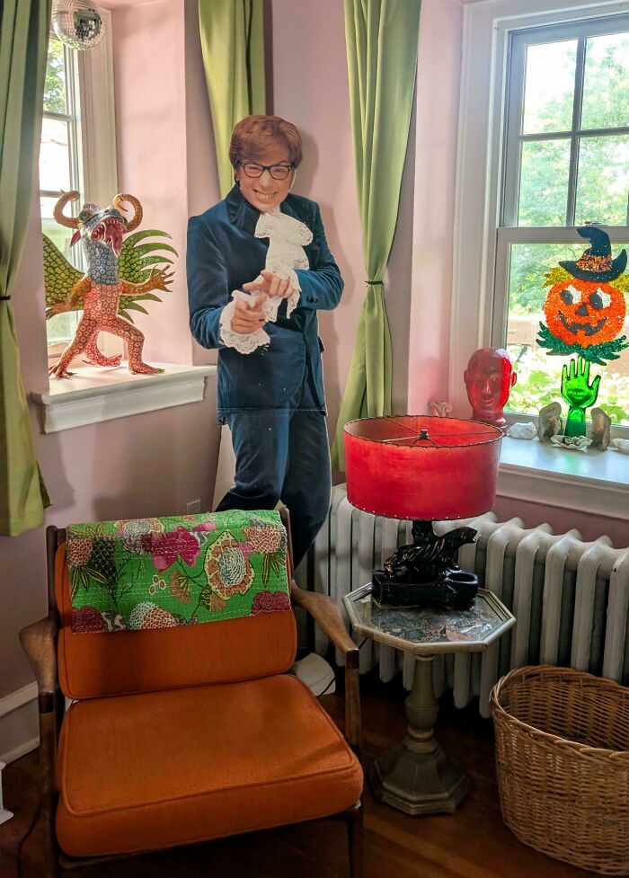 An Austin Powers cardboard cutout, a unique thrift store jackpot, stands in a colorful room with vintage decor.