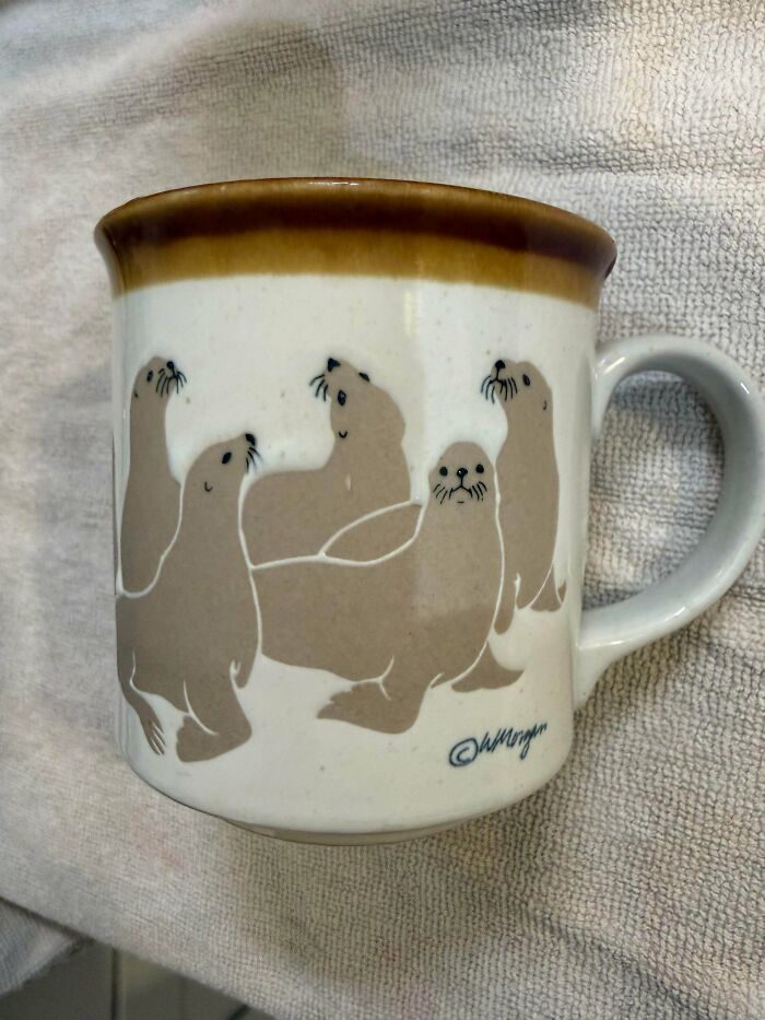 White mug with brown rim featuring playful seals, an adorable thrift store jackpot find.