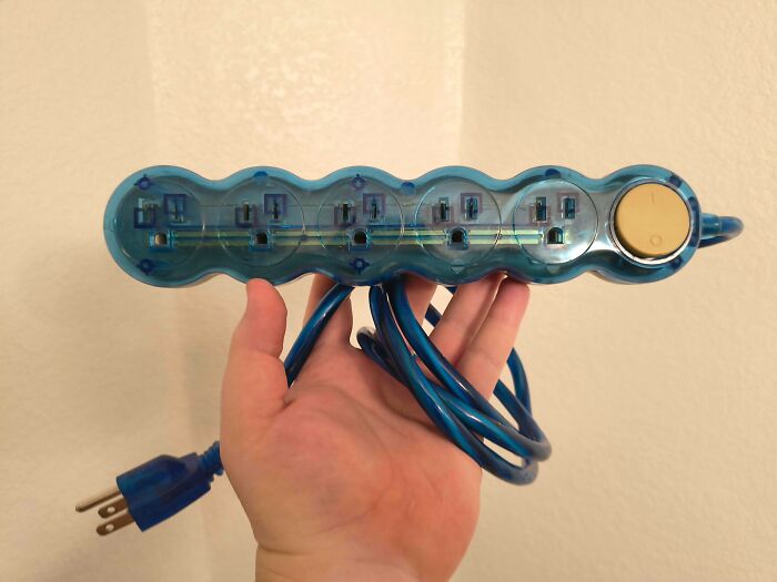 Blue, translucent power strip held by a hand, a great thrift store jackpot for electronics.