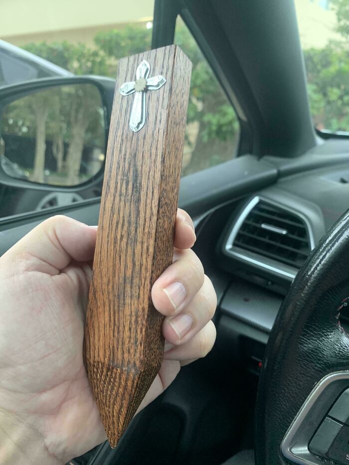 A hand holding a wooden stake with a silver cross, a thrift store jackpot item.