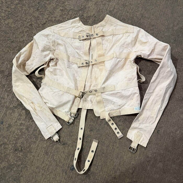 An old, canvas straitjacket with buckles and straps, a rare find hitting the jackpot at a thrift store.