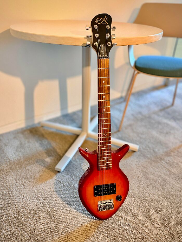 A unique, small red electric guitar with a fish symbol, a jackpot find at a thrift store.