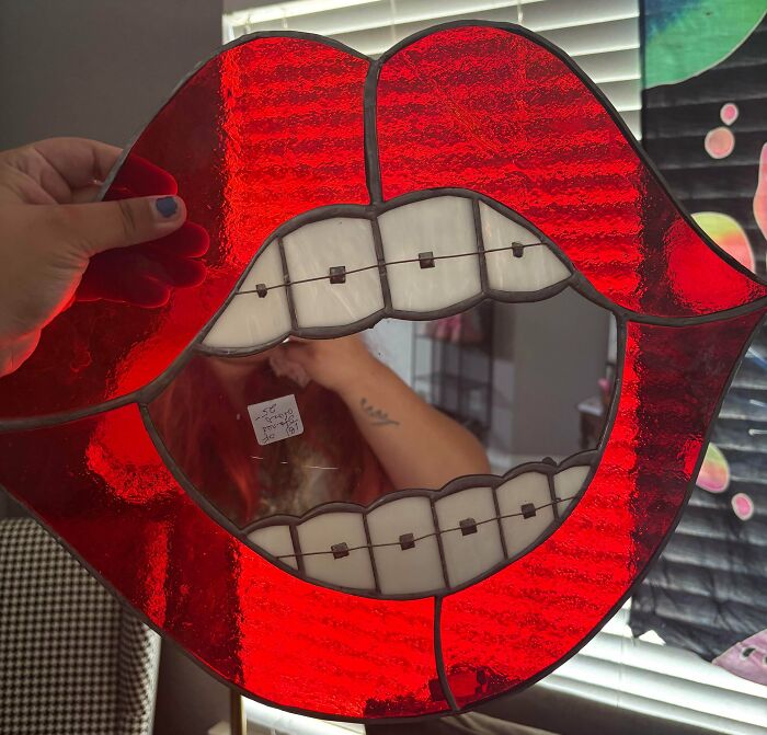 A red stained-glass lips art piece with mirrored teeth and braces, a fun jackpot from the thrift store.