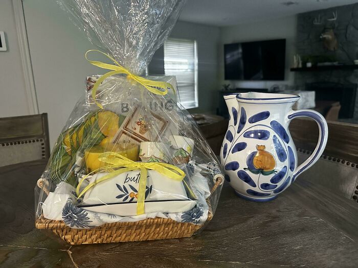A wicker gift basket filled with kitchen items and a ceramic pitcher, a delightful jackpot from the thrift store.