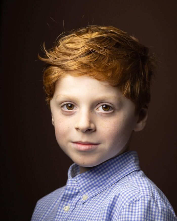 A young natural redhead boy with bright eyes and a checkered shirt, from a global portrait project.