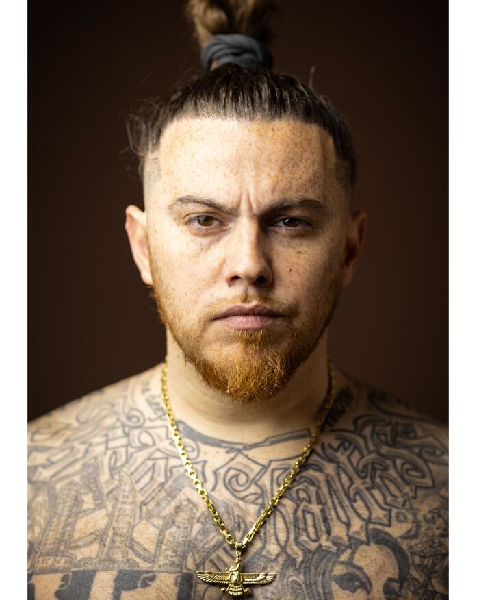 Portrait of a man with a red beard, a top knot, and tattoos, highlighting natural redheads.