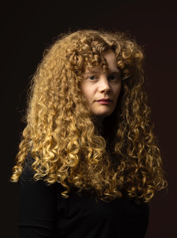 Portrait of a natural redhead woman with long, curly red hair, part of a global portrait project.