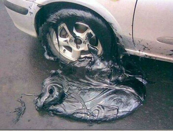 A car tire completely melted into a puddle of black goo, a result of summer melting everything.