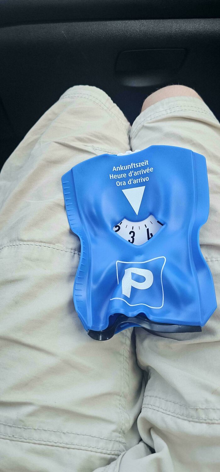 A person holding a blue parking disc that is visibly melted and ruined by the summer heat.