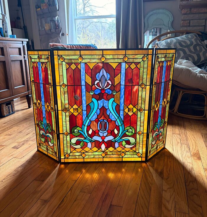A stunning stained glass fireplace screen, a beautiful thrift store jackpot, illuminating a room.