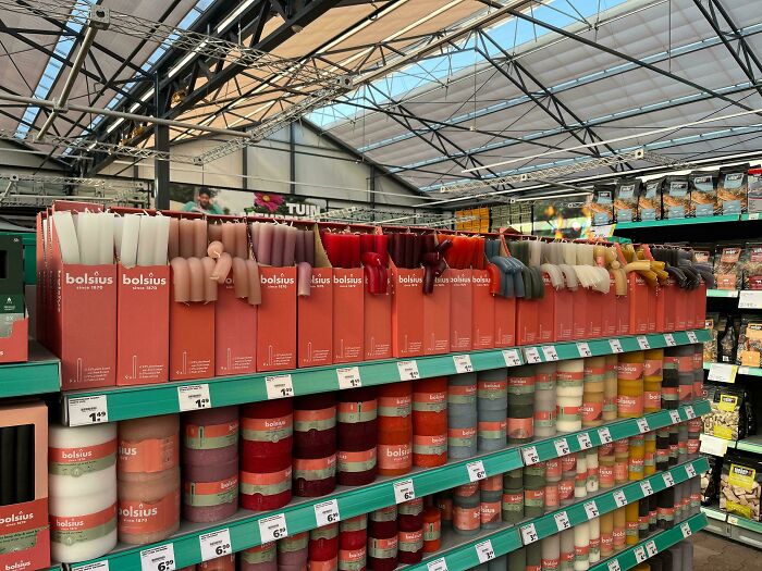 Shelves in a store displaying various candles, some of which appear to be slightly warped from summer melting.