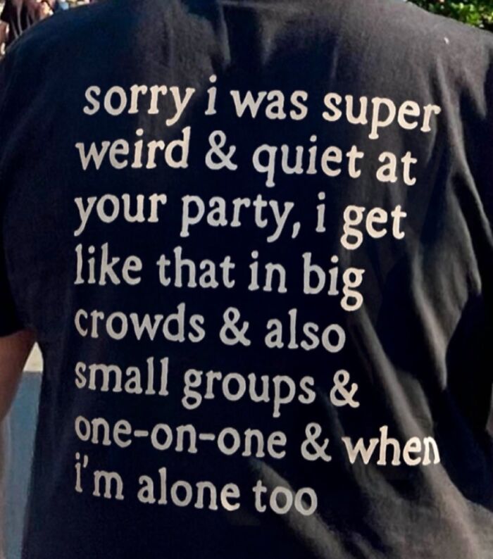 A black iconic shirt with text on the back: sorry i was super weird & quiet at your party, i get like that in big crowds & also small groups & one-on-one & when i'm alone too.