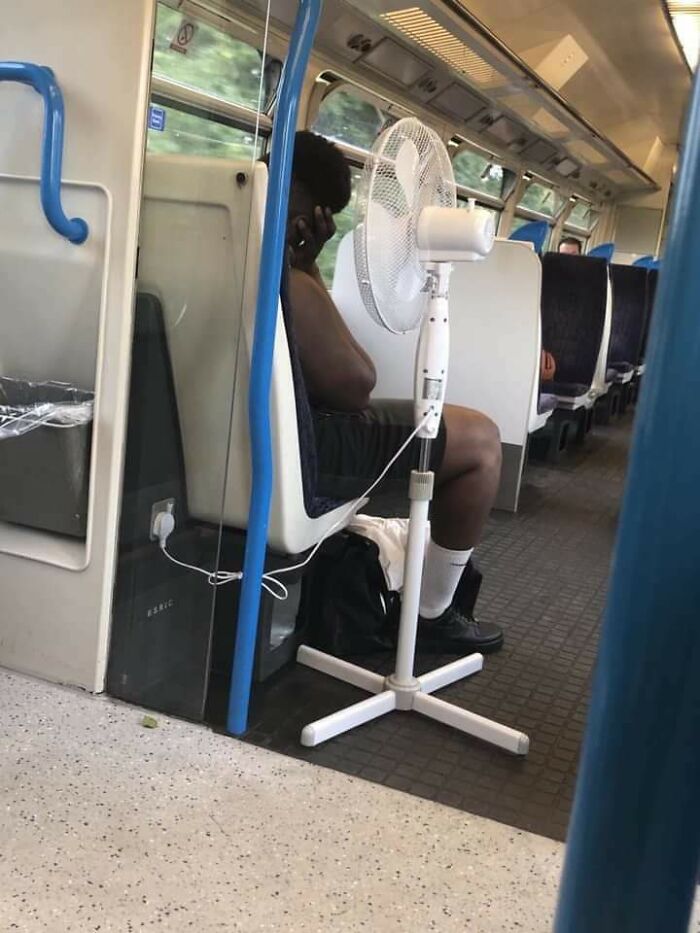 Man on a train with a fan, showing summer melting everything.
