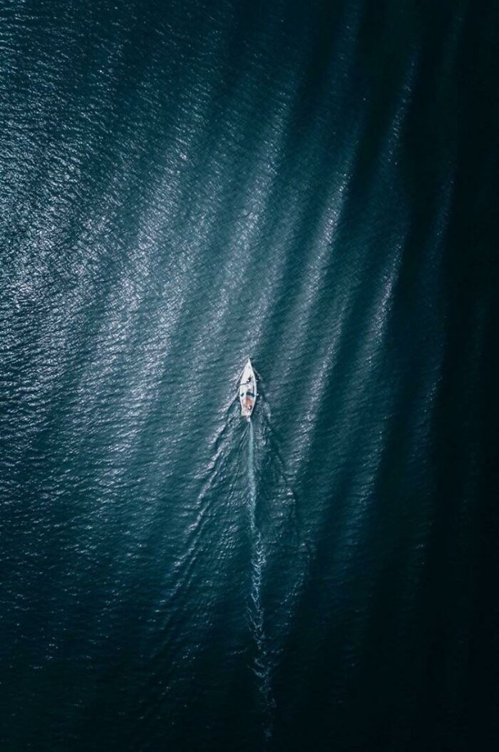 A confusing pic of a small boat on vast, dark blue water from an aerial view, a misleading headline.