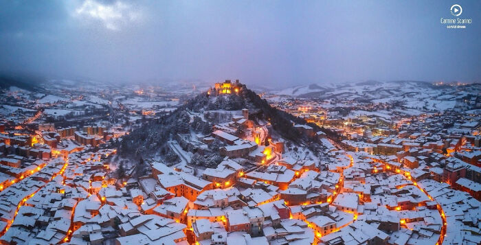 A confusing pic of a snow-covered mountain town with a castle lit up at dusk, creating misleading headlines.