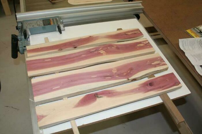 Four planks of cedar wood with vibrant purple grain next to a table saw, a misleading headline pic.