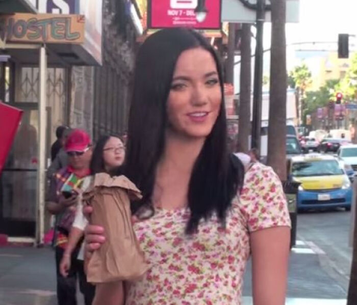 A woman holding a brown paper bag in a confusing pic with a misleading headline on a city street.