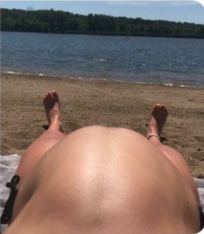 A misleading headline pic of a pregnant woman sunbathing on a sandy beach by a lake.