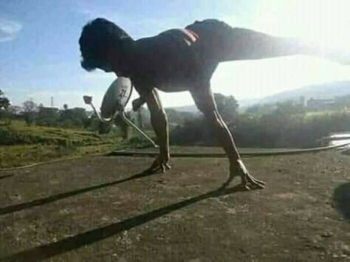 A person in a contorted pose holding a satellite dish, creating a confusing pic with a misleading headline.