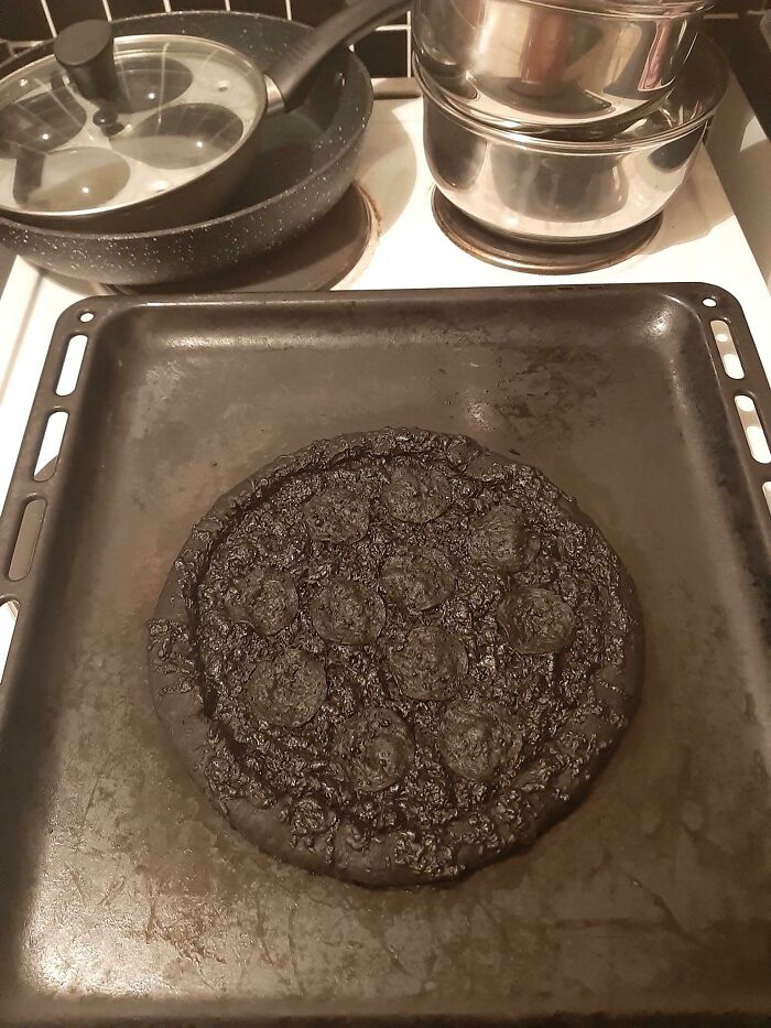 A completely burnt, black pizza on a baking sheet, a confusing pic with a misleading headline.